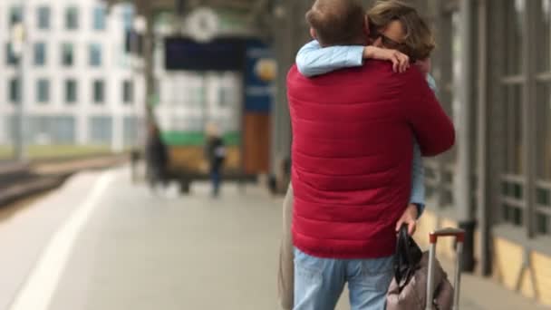 Mujer madura se encuentra en la estación de su marido del viaje. Reunión largamente esperada — Vídeos de Stock