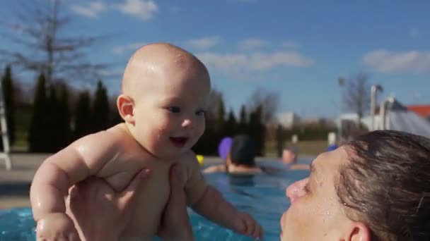 Ευτυχισμένο μωρό με πατέρα πιτσίλισμα στην πισίνα. Το παιδί κόλλησε τη γλώσσα του έξω από ευχαρίστηση. Γκρο πλαν, πιτσίλισμα νερού — Αρχείο Βίντεο