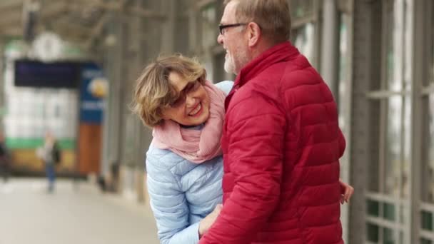 Enamorado pareja de ancianos se reunieron en la estación. Un hombre y una mujer abrazan y ríen. Día de San Valentín — Vídeos de Stock