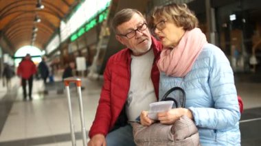 Casual yaşlılar çift tren istasyonu bankta oturan ve tren gelmesi beklenirken sohbet