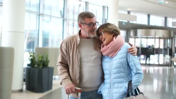 Pár důchodců na letišti. Pohlédli na sebe a šťastně se usmívají. Cíl cesty — Stock video