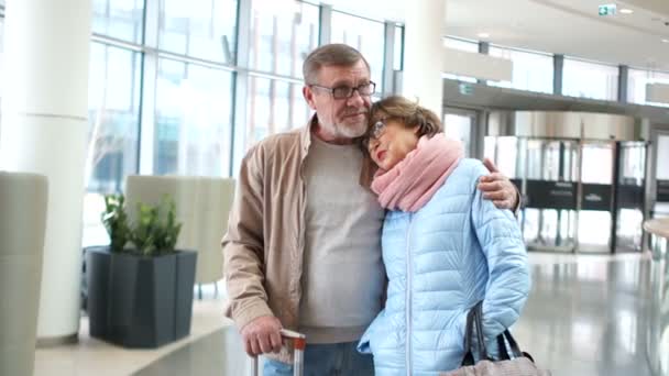 Seyahat gösterimleri. Havaalanında bir adam ve orta yaşlı bir kadın uçuşlarını bekliyorlar. Güzel bir yolculuğun başlangıcı — Stok video