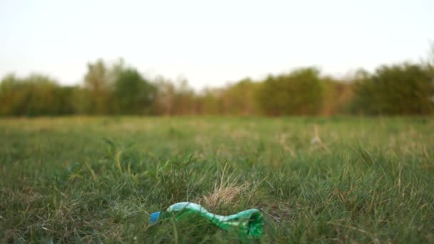 Mano femminile in un guanto di gomma blu raccoglie una bottiglia di plastica dall'erba. Stop concetto di plastica, volontari ambientali — Video Stock