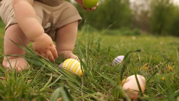 Bebek bacaklarının yakın çekim. Bir çocuk çimenlerde Paskalya yumurtası arıyor. Mutlu paskalya ailesi — Stok video