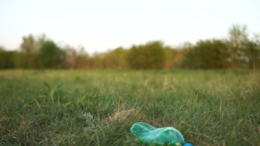 Yakın plan bir gönüllü nün eli parktaki çimenlerden plastik bir şişe alır. plastik durdurmak, sosyal kavram, sivil sorumluluk, çevre kavramı