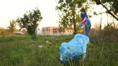 Kadın şehir parkından çöp topluyor. Sosyal sorumluluk, çevre girişimi, vatandaşlık, plastiği durdurun
