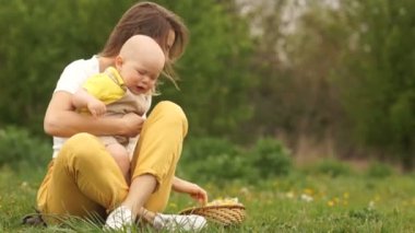 Kızgın bebek annesinin kollarında. Bebek ağlıyor, anne sakinleşti. Kadın ve bebek parkta piknikte