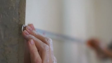 Bir erkek ve bir kadın yeni dairelerinde duvardaki mesafeyi ölçerler. Onarım, inşaat, tasarım konsepti. Kendi evlerinde mutlu yeni evliler