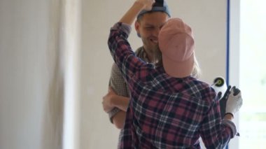 Aşık yeni evliler yeni evlerinde duvarları boyarlar. Yeni aile, erkek ve kadın kendi, romantik onarım onarım yapmak