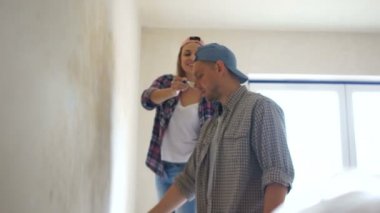 Ev yenileme, mutlu yeni evliler yeni daire duvara boyama ve raf asmak. Emlak