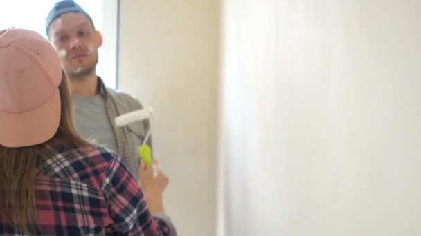 Home repair. Happy newly-wed couple paint the walls in their new home. Fanny videos, boy and girl paint each other joking — Stock Video