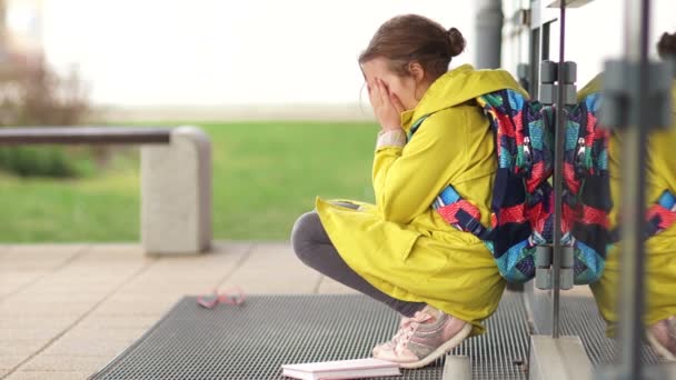 Einsames Mädchen, das vor Beleidigung weint und vor der Tür der Schule sitzt. nimmt eine Brille und eine Anleitung und geht. Bulling-Konzept — Stockvideo