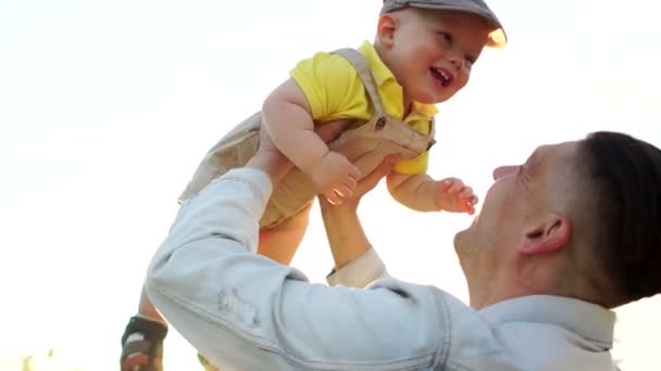 Feliz familia caminar en parque padre jugar lanzar hasta pequeño bebé hijo en el aire y atraparlo — Vídeos de Stock
