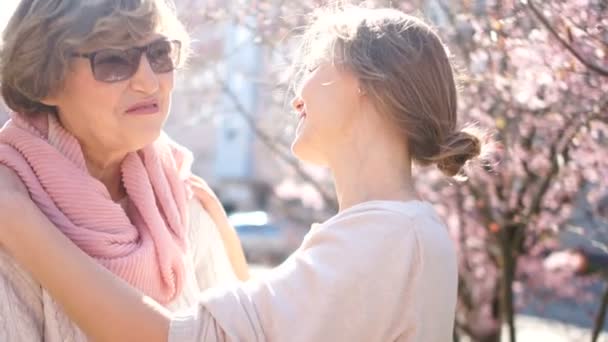 Talking mother and adult daughter on the street in the spring. Bright morning sun, mothers day, daughters day — Stock Video