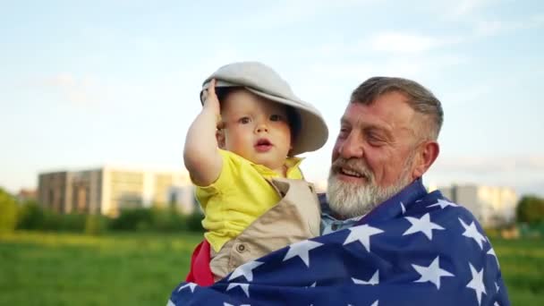 USA självständighetsdagen, 4 juli. Farfar och lilla barnbarn firar självständighetsdagen. Funny baby i en mössa, flagga USA — Stockvideo