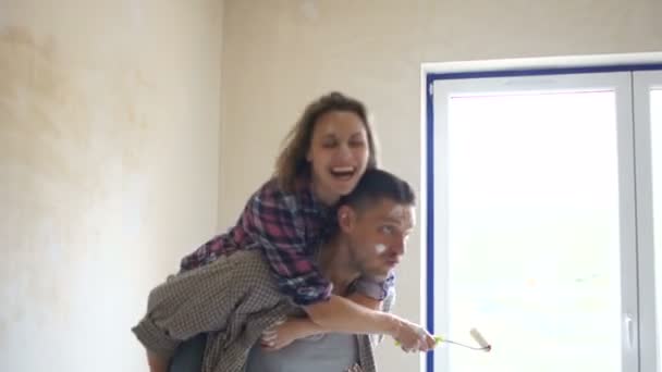 Забавное видео молодой жены на плечах мужа, прыгающего на новую квартиру во время ремонта. Новоселье, недвижимость, ремонт дома. Быстрое воспроизведение видео — стоковое видео