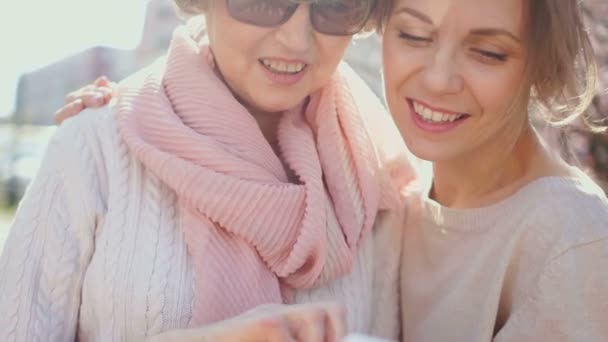 Dos mujeres discutiendo fotos en el smartphone. Retrato de primavera en el parque. Comercialización de redes, negocio MLM — Vídeo de stock