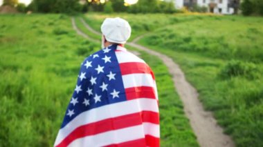 Bir adam, amerikan bayrağının omuzlarında, arka görüşte uzaklaşıyor. Vatansever gün, ölen Amerikan askerlerinin anısına gün.