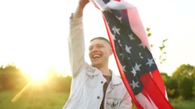 Amerika Birleşik Devletleri Bağımsızlık Günü kutlamaları, 4 Temmuz, ABD. Batan güneşin ışınlarına karşı bayrak sallayan bir adam.