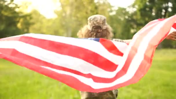 USA flag is held by a running guy in camouflage on the background of a summer park and sky Outdoor Patriotic day — Stock Video