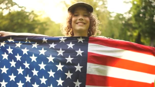 Amerikanska skolpojke innehar en stor USA flagga och leende. Närbild porträtt. USA självständighetsdagen — Stockvideo