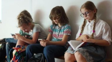 Onun sınıf arkadaşları akıllı telefonlar, yakın bir portre ile oynamak ederken pigtails ve gözlük ile mükemmel bir öğrenci, bir okul molası sırasında bir kitap okur. Onur öğrencisi