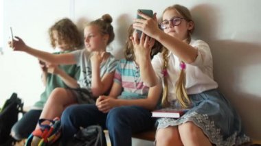 Okul koridorda oturan ve bir grup selfie yapan gençler bir grup. Çocuklar ve Gadgets