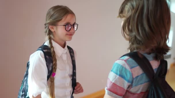 Skol kärlek. Pojken och flickan pratar i skolans korridor, pojken kommer närmare och kramar flickan, de skämmer ut — Stockvideo