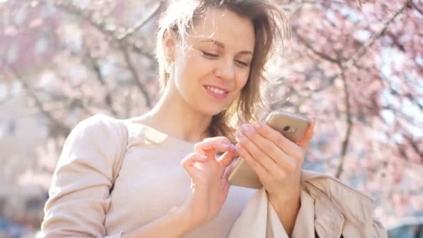 Tecnología en nuestra vida. Retrato de una hermosa joven con un teléfono inteligente en sus manos — Vídeos de Stock