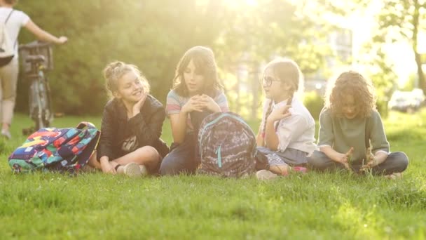 Niños, niñas y niños felices se apresuran con las mochilas durante las vacaciones escolares. De vuelta a la escuela, un grupo de adolescentes en un picnic. Atardecer rayos solares — Vídeo de stock