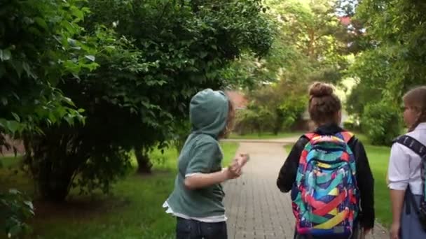 Beginn der Sommerferien, Ende des Schuljahres. Kinder laufen spaßig aus der Schule und wedeln mit Rucksäcken über den Köpfen — Stockvideo