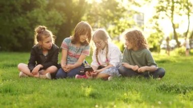 Okul tatilinde çimlerin üzerinde oturan bir grup genç. Dört çocuk, erkek ve kız izlemek ve onlardan birinin elinde akıllı telefon tartışmak. Çocuklar ve Araçlar Okula Geri Dönüyor