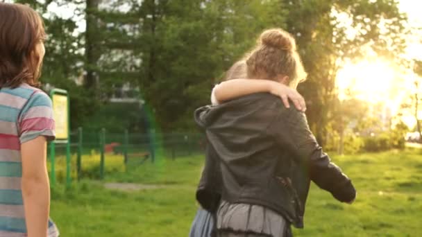 Gut gelaunte Klassenkameraden rennen im Park vor der Kulisse des Sonnenuntergangs in die Ferne. zurück zur Schule, glückliche Kinder — Stockvideo