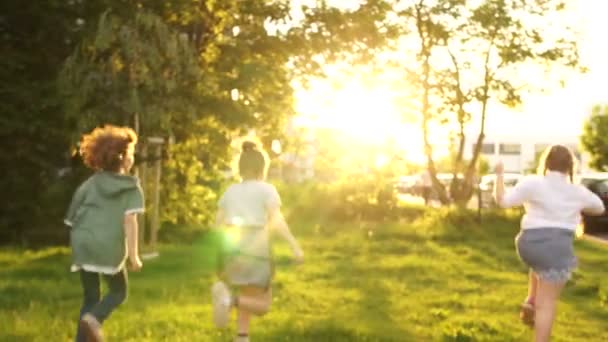 Bambini felici che giocano in un parco cittadino. Riflesso del sole al tramonto, coniglietto soleggiato, concetto di infanzia felice, giochi per bambini — Video Stock