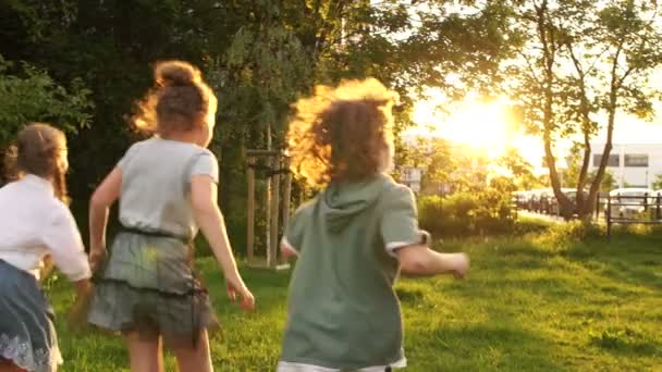 Los compañeros de clase adolescentes juegan en el parque durante el recreo escolar. Deslumbramiento del sol al atardecer — Vídeos de Stock