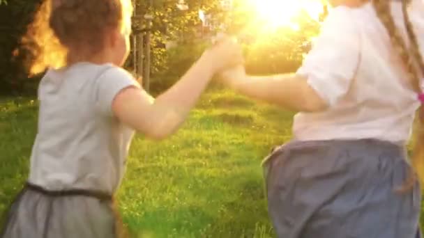 Achteraanzicht, twee meisjes schoolmeisjes lopen in de verte door het stadspark. Gelukkige kindertijd, school vriendschap, terug naar school — Stockvideo