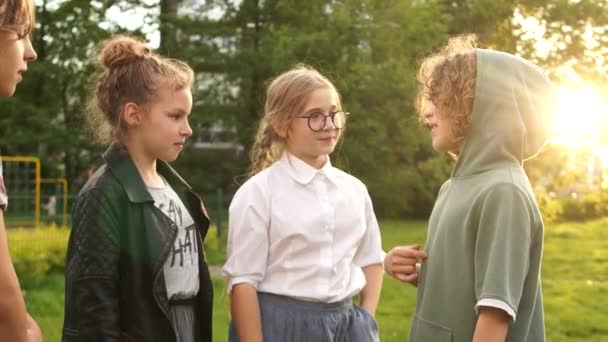 Los niños compañeros de clase hablan entre sí durante un paseo por el parque, la amistad escolar, de vuelta a la escuela. Puesta de sol, Bengala lins — Vídeos de Stock