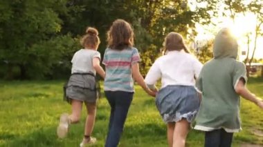Mutlu çocuklar. Dört sınıf arkadaşı birbirlerine sarıldı ve yeşil ağaçlar ve gün batımı fon karşı mesafe koştu. Okul arkadaşlığı, okula geri, lens parlama