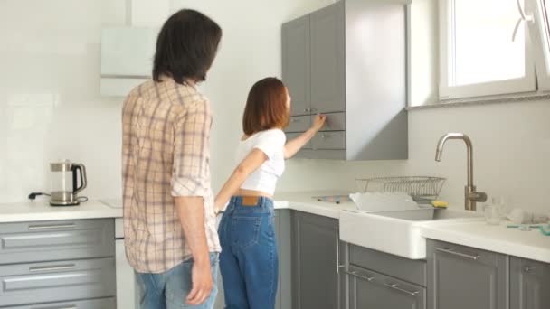 El hombre y la mujer son felices comprando un nuevo apartamento. Los recién casados en la cocina están contentos con los nuevos bienes raíces — Vídeo de stock