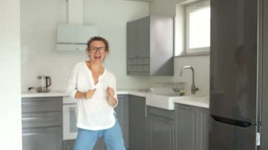 Restorasyon tamamlandıktan sonra yeni mutfağında dans eden güzel bir genç kadının portresi. Gayrimenkul onarım konsepti