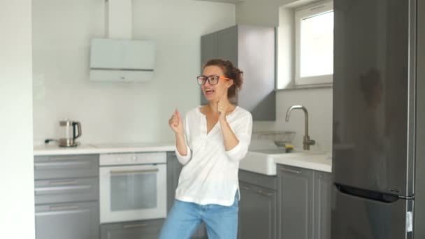 Fanny video portrait of a beautiful young woman dancing in her new kitchen after the repair is completed. Real estate repair concept — Stock Video