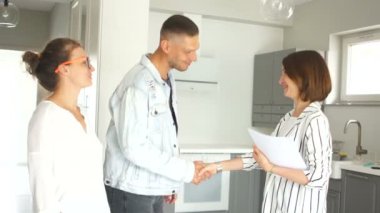 Mutlu genç çift ilk kez ev alıcılar kiracılar imza Mortgage kredi yatırım sözleşmesi satış satın alma anlaşması gayrimenkul anlaşma toplantı emlakçı yapmak, müşteriler yeni ev anahtarları el sıkışması Ajan olsun