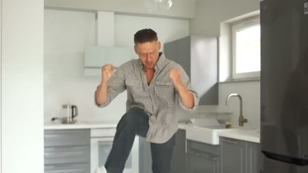 Vastgoed concept. Jonge aantrekkelijke man dansen grappig in zijn nieuwe keuken. Licht interieur, gerenoveerd in een nieuw appartement — Stockvideo