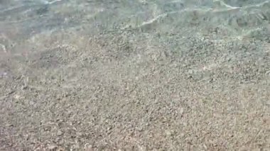 Kıyıya, küçük çakıl taşları açık deniz suyu. Turkuaz deniz suyu closeup. Ekoloji ve seyahat konsepti