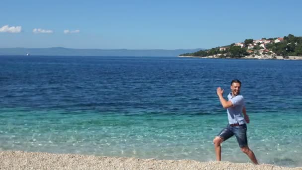 ファニービデオの女性は、男に追いつく。ペアは服を着て水の中を走る。アドリア海沿岸 — ストック動画