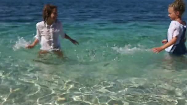 I bambini felici si divertono nell'acqua cristallina del mare. Ragazzo e ragazza schizzare e ridere — Video Stock