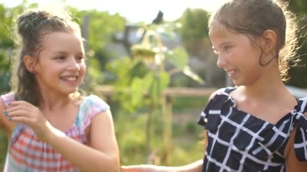 Twee meisjes schoolmeisjes vriendin springen in spray van water. Zomer vakantie, goed humeur, gelukkige kinderen — Stockvideo