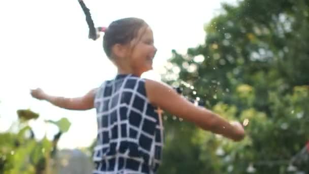 Szoros portréja egy boldog tinédzser lány Pigtail nyáron nyaralni a faluban. Lány spinning a spray a víz naplementekor — Stock videók