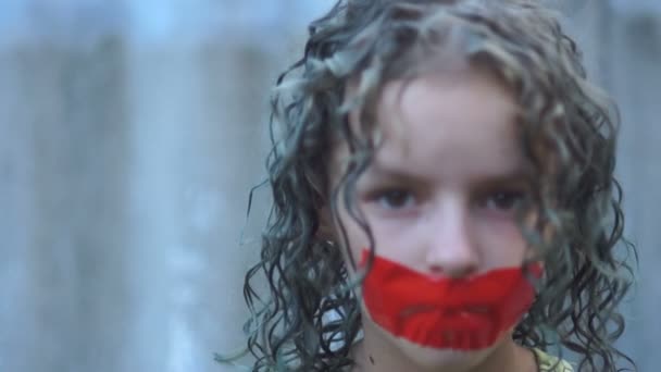 Close-up portret van een krullend verdrietig tiener meisje met haar mond geplakt met rode tape. Schending van de vrijheid van meningsuiting en censuur concept — Stockvideo