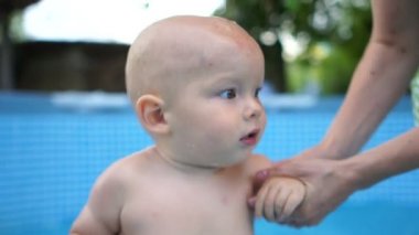 Havuzda su akıntısı altında bir yaşında bir çocuk. Bir yaşındaki bir çocuğu eğitmek, nefesinizi tutmak ve dalmak için eğitim almak, sertleşmek
